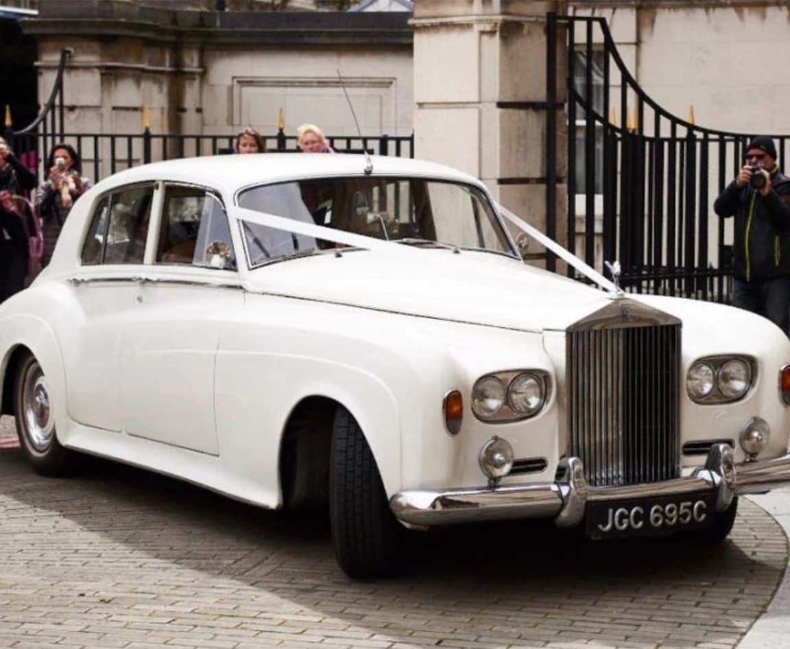 white 1930s Rolls Royce decorated with white ribbons for a Mayfair wedding 
