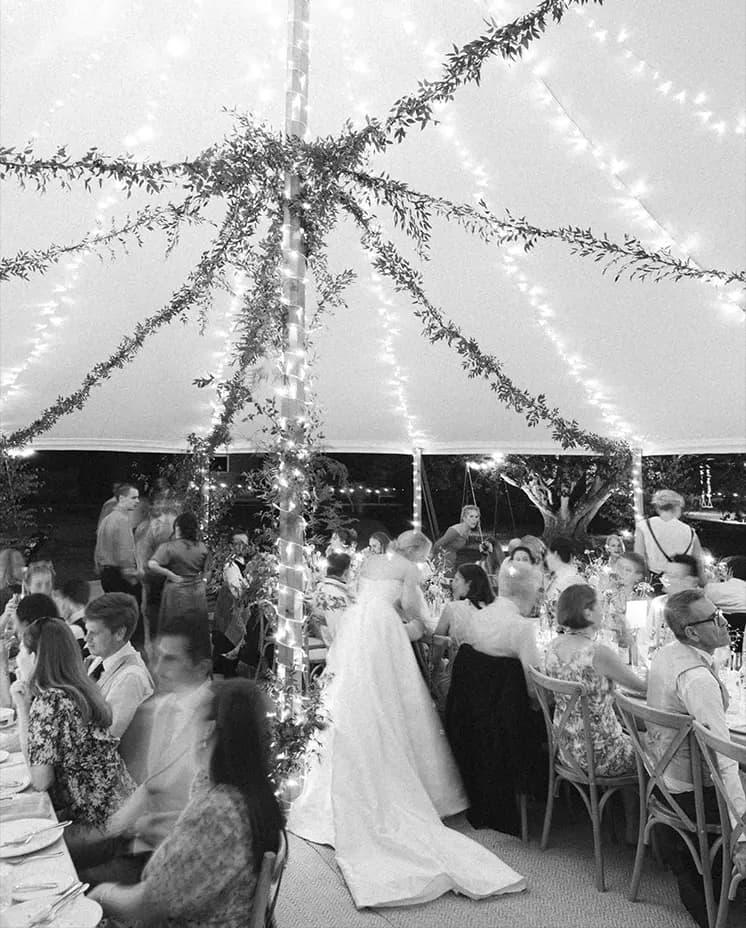 A wedding party inside decorated traditional marquee at night
