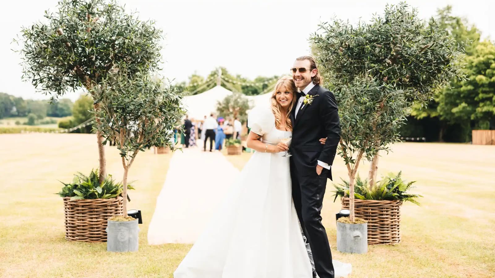 bride and groom standing next to olive trees at Tuscan-inspired wedding