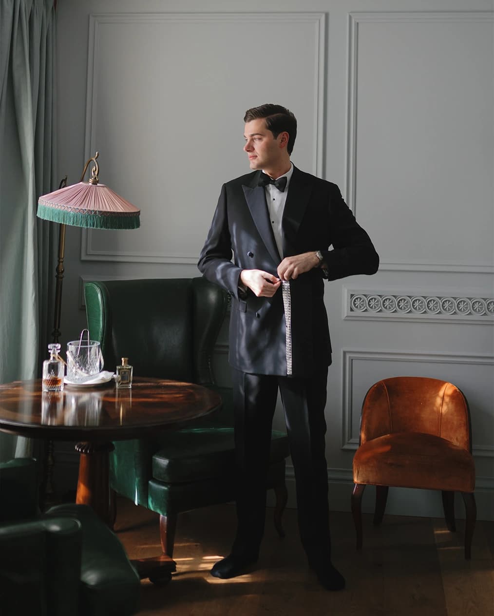 Groom in suit get ready in his hotel suite ahead of wedding ceremony