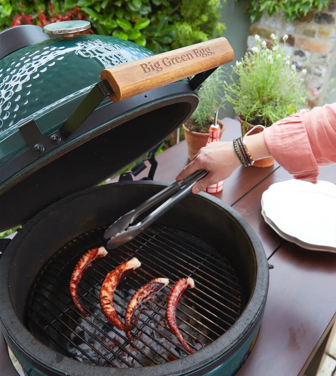 A person grills octopus on the Big Green Egg BBQ, gifted as the group gift from The Wedding Present Company.