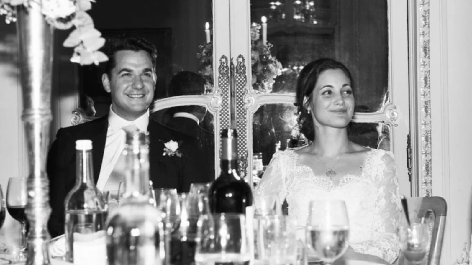 Bride and Groom sitting next to each other at their wedding breakfast with glasses of wine on the table