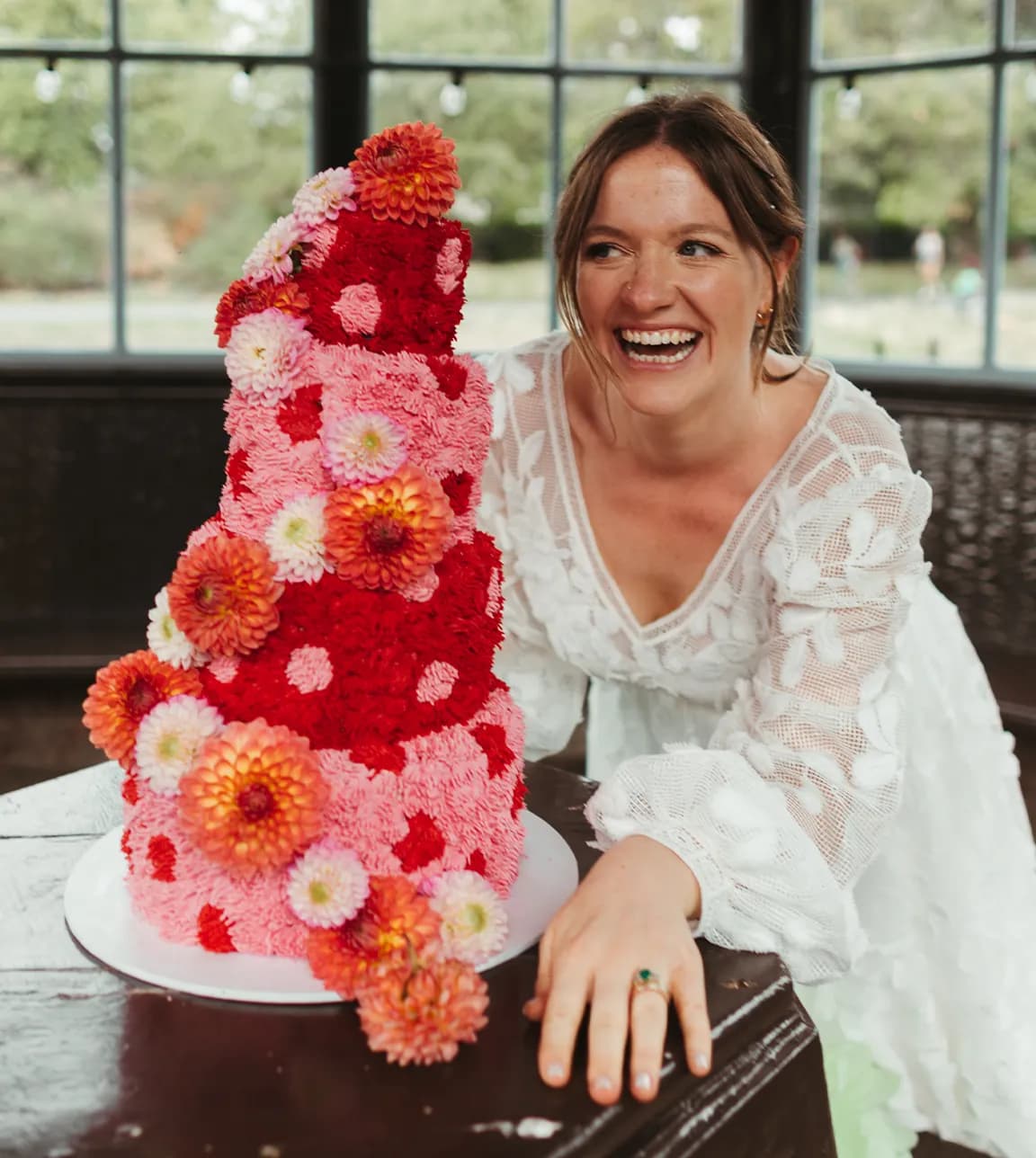 Beautiful bride smiling with colourful floral cake 