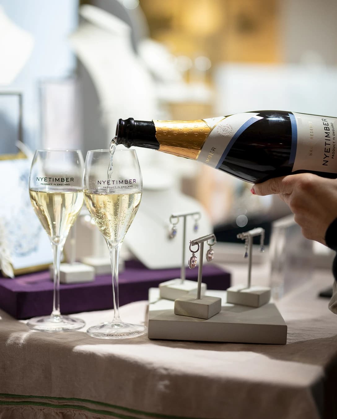 A showcase display of Kiki McDonough jewellery with glasses with Nyetimber sparkling wine