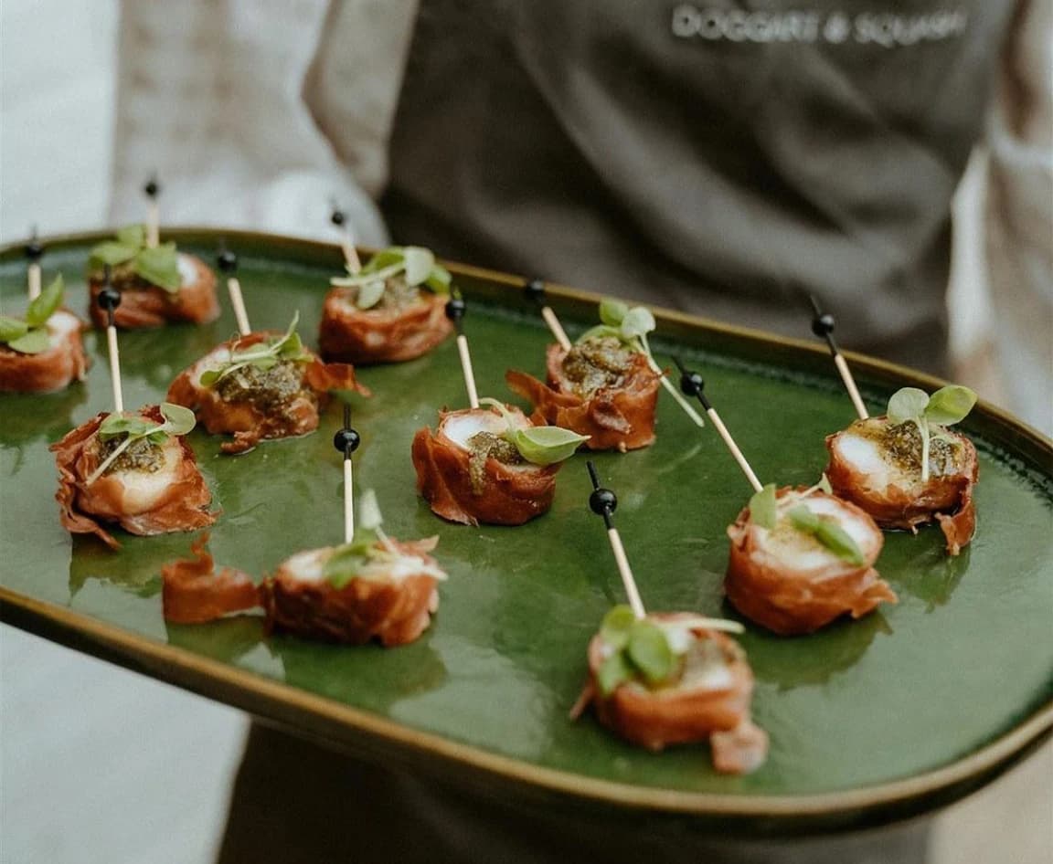 Wedding catering canapes are served on a green platter.