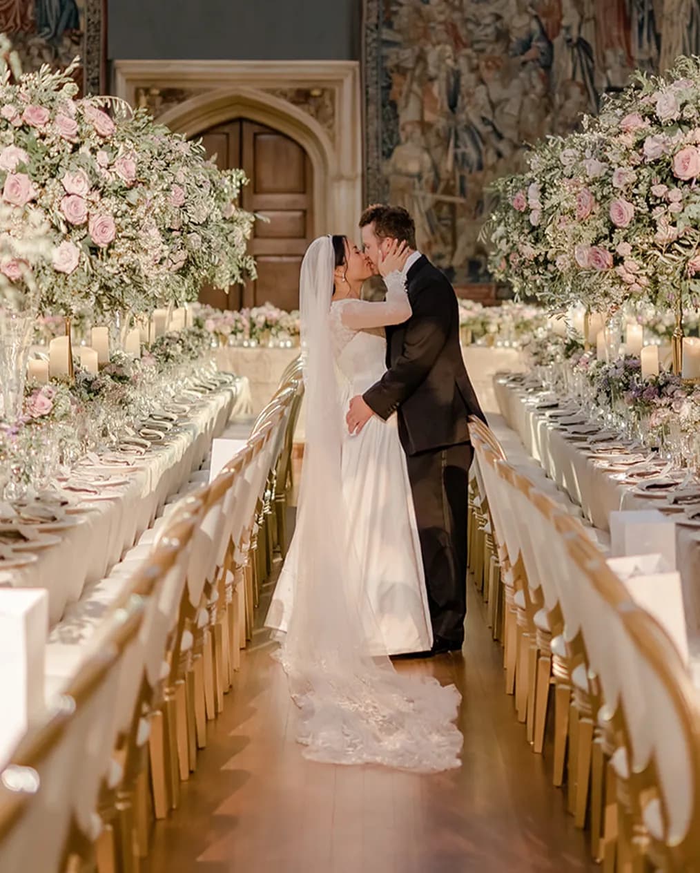 Bride and groom are kissing amidst the wedding flower decoration at Hampton Court Palace