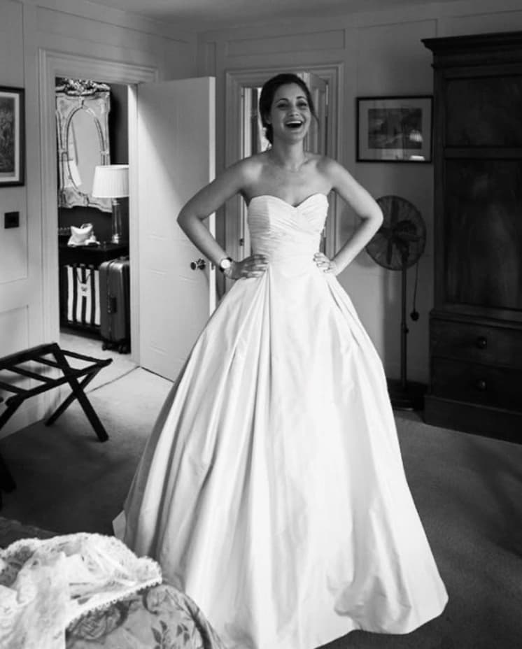 Smiling bride getting dressed in hotel room with hands on hips