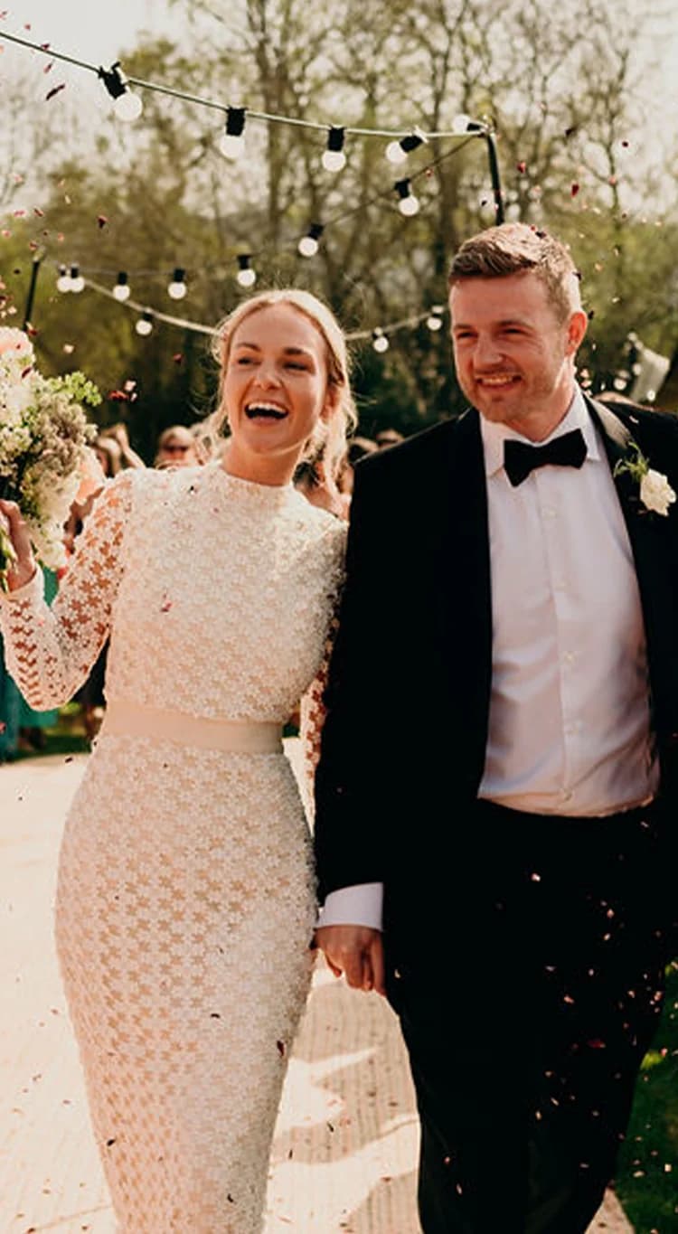 Guest throwing confetti on traditional bride and groom