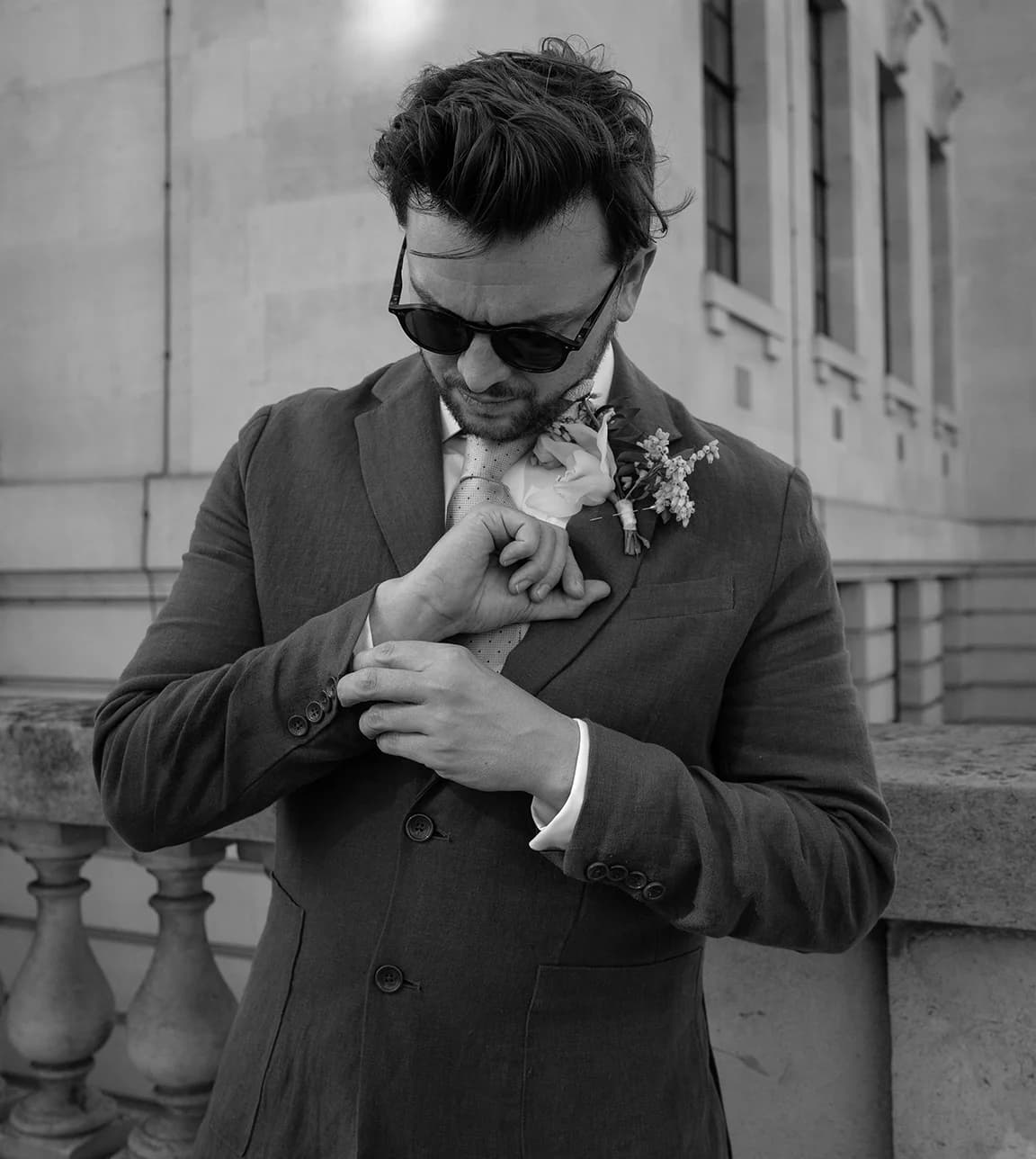 Groom wearing RayBan sunglasses and linen suite with boutonnière