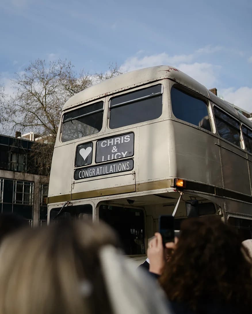 A classic white route master bus with the newlyweds name on it
