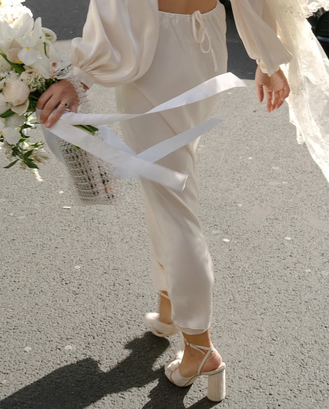 Bride walks in Loeffler Randall heels holding wedding bouquet in hand