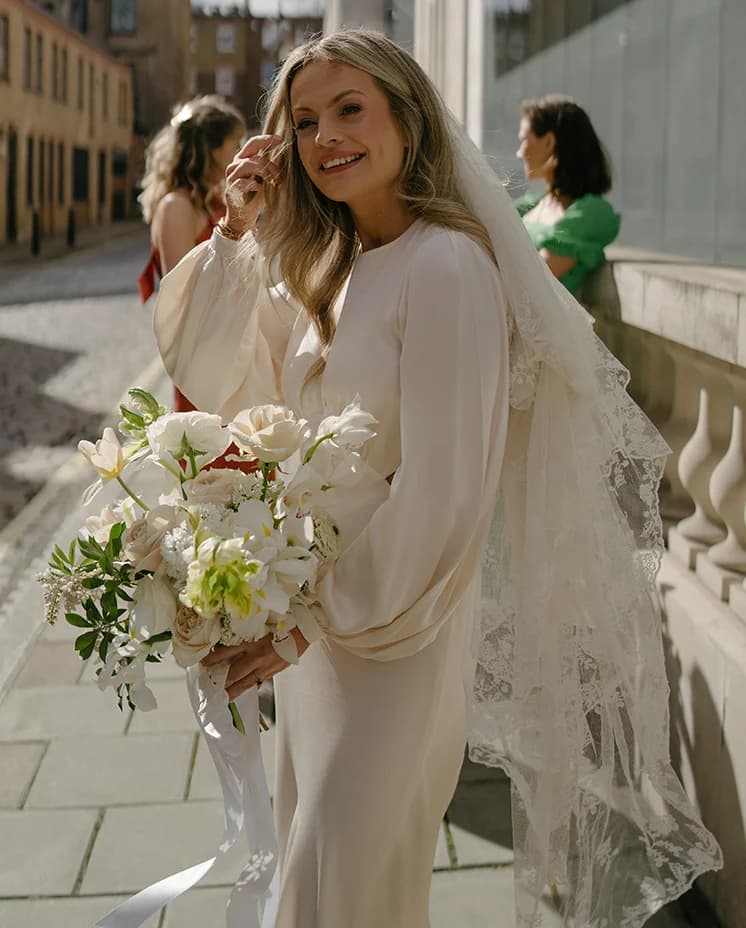 Bride wearing Shona Joy silk wedding gown with balloon sleeves and vintage veil