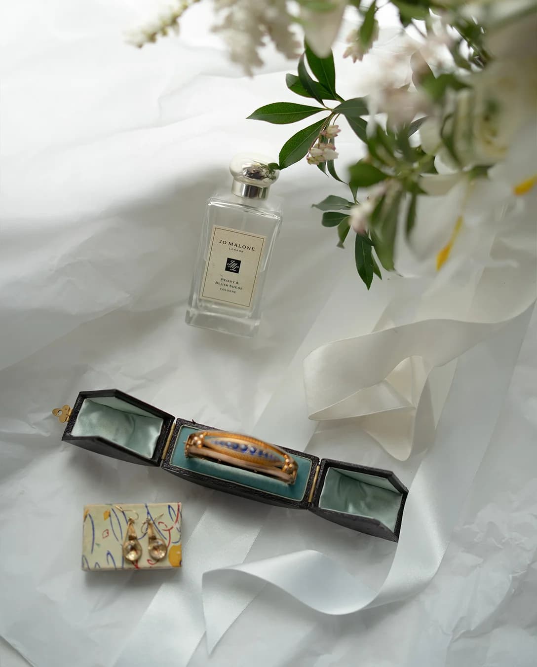 Heirloom bridal jewellery pieces, bracelet and earrings, next to Jo Malone perfume bottle