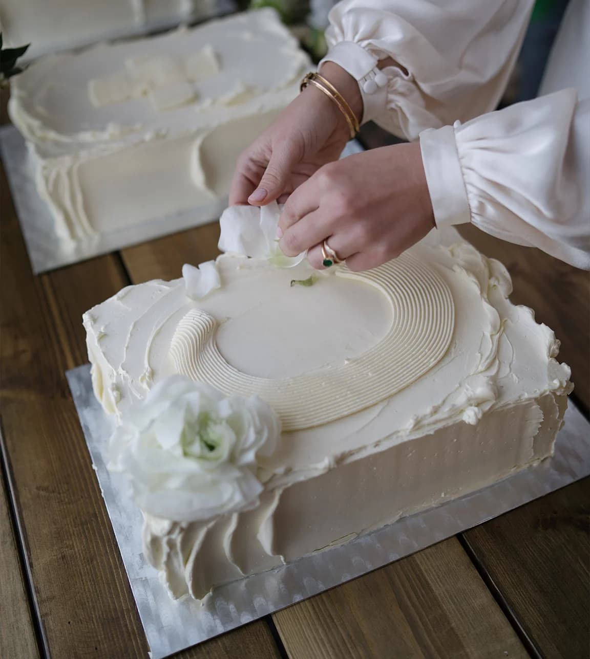 A minimal wedding cake with flowers and the initial 'C'