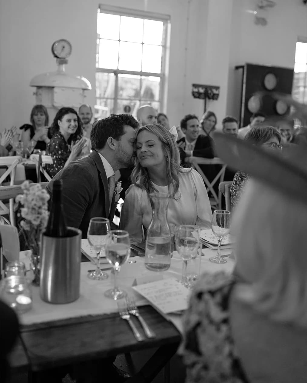 Newlyweds sat behind the table are enjoying each other during their wedding reception at West Reservoir Centre