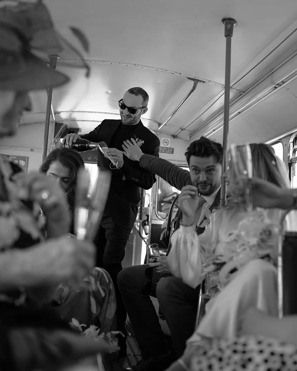 Wedding guests and newlyweds enjoy wedding drinks being served on their transport bus
