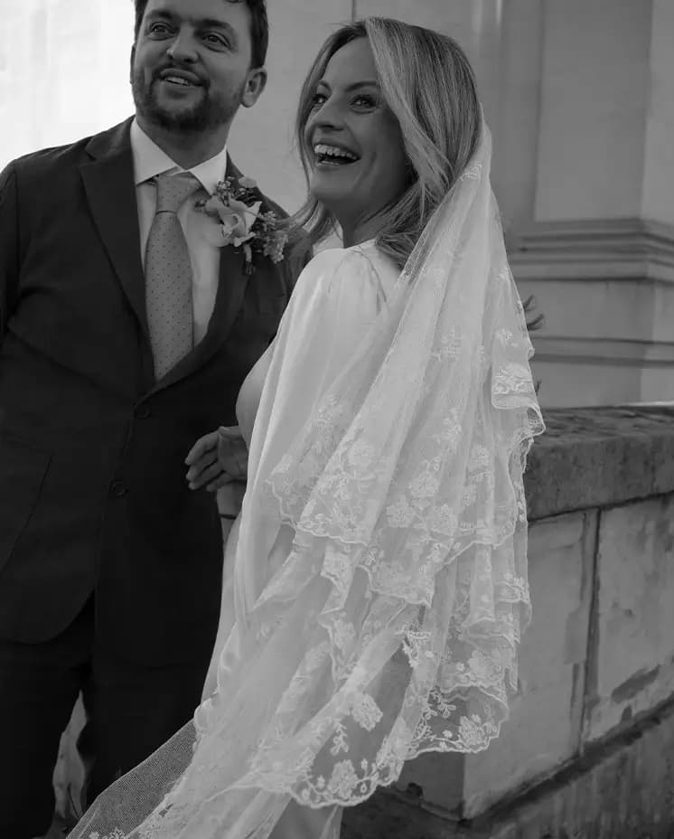 Groom in green linen suit and bride in silk wedding dress with vintage veil are looking back