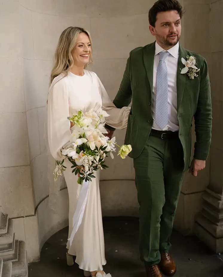 Bride and groom pose next to a stone wall of Marylebone Town hall