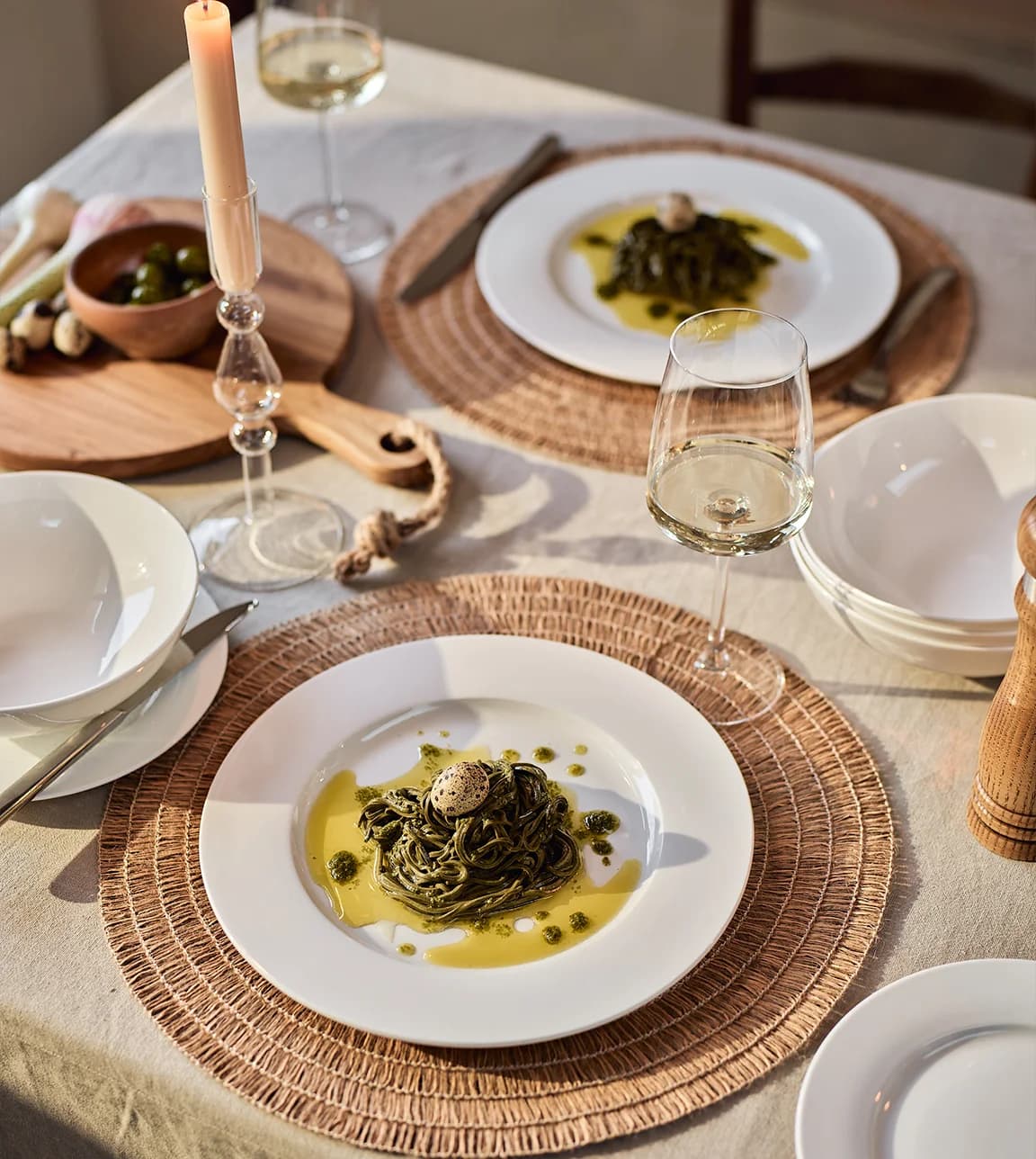 A simple casual table setting featuring Wren & Wilder tableware including a dinner set, woven place mats and glass candleholder