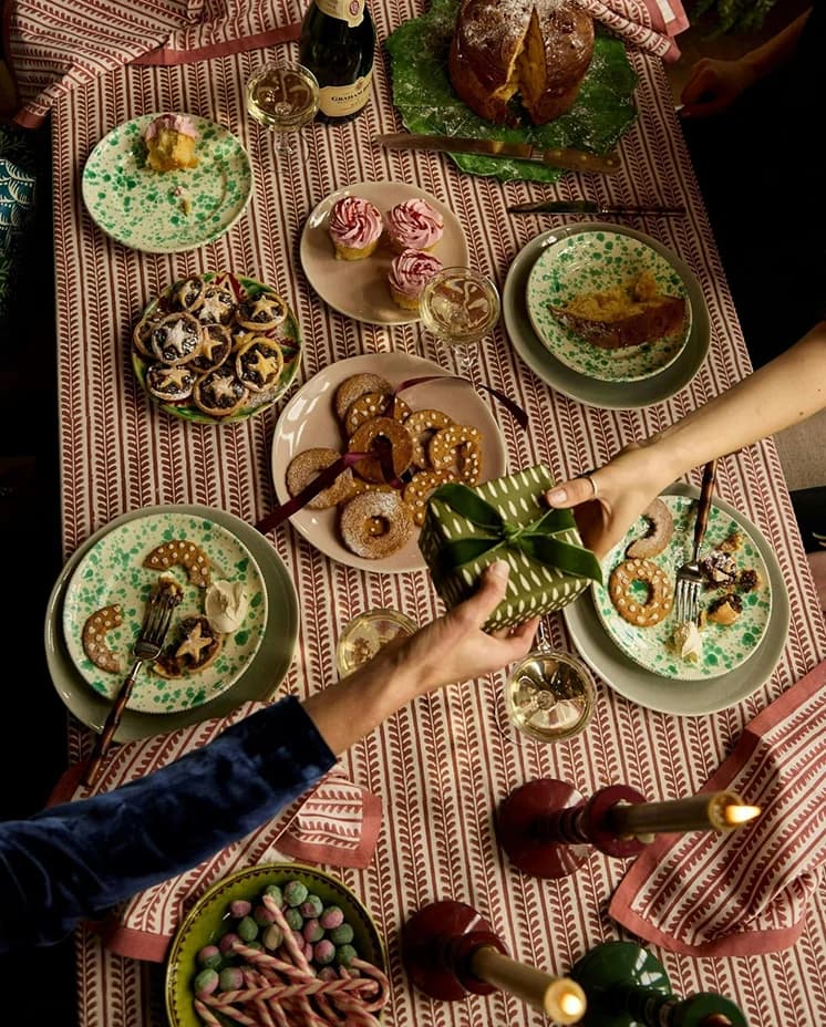 People pass gifts over festive table setting