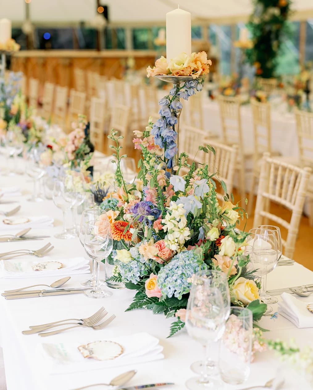 A wedding marquee with colourful floral decor and tall candles