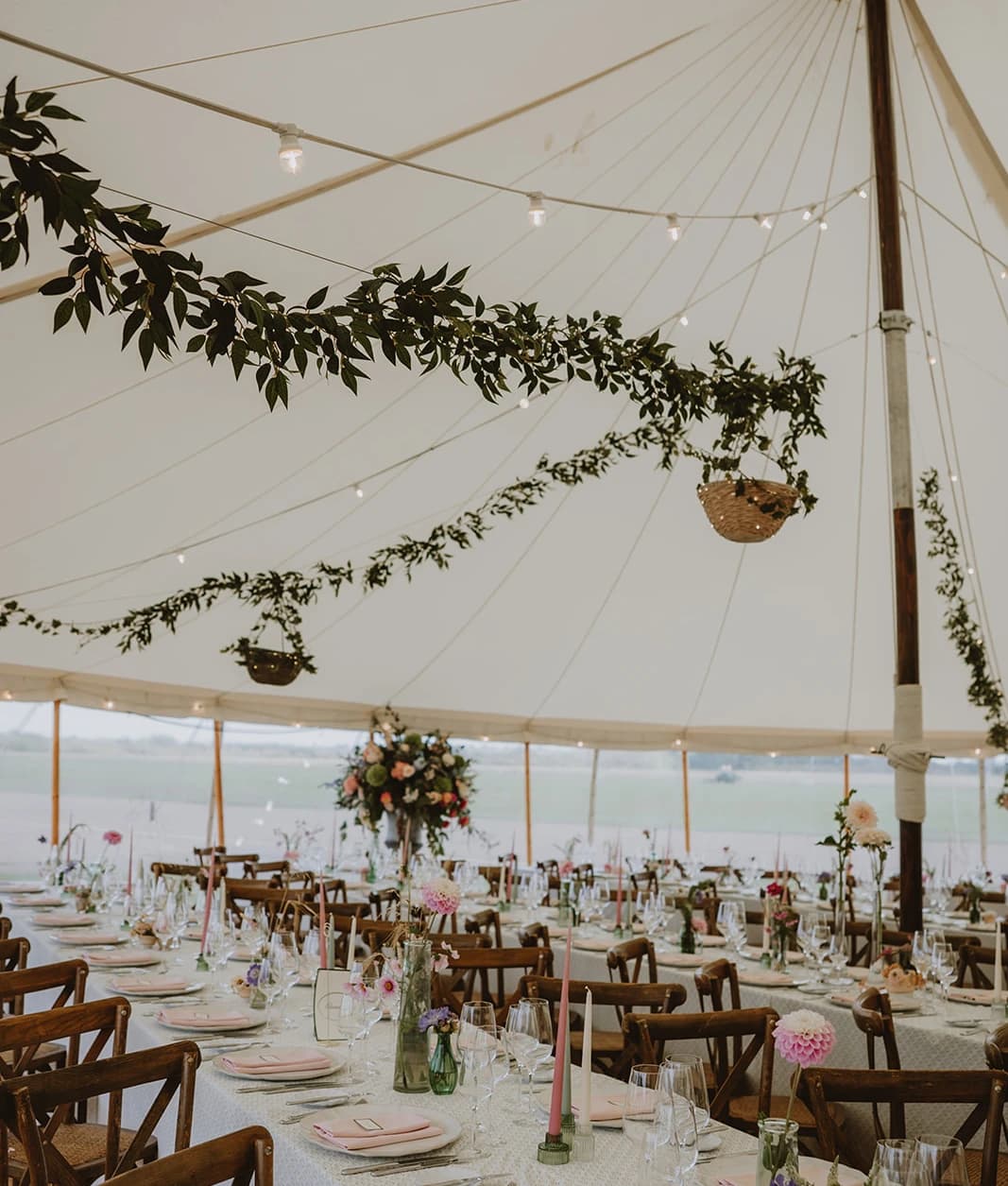 Wedding marquee with hanging baskets, foliage garlands and long tables set for dinner
