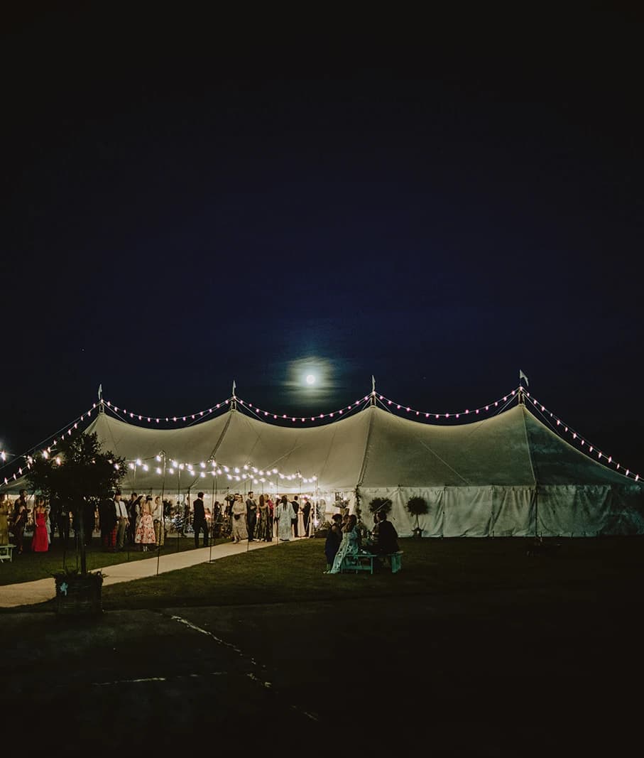 Wedding marquee lit with festoon lights on the airfield at night