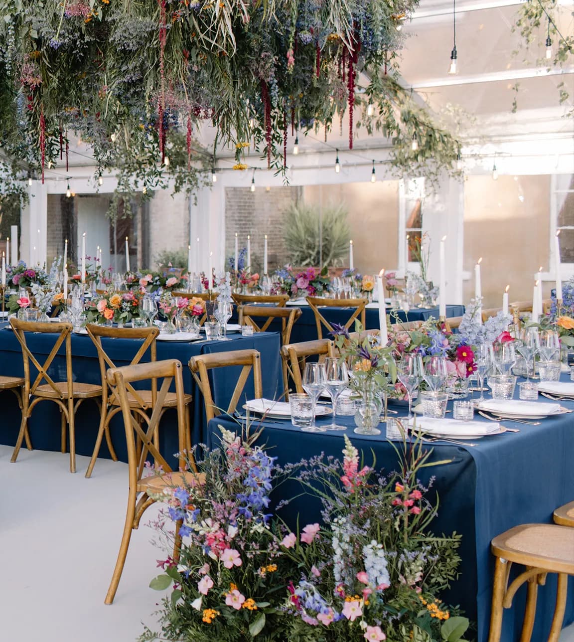 Wedding tables decorated with blue tablecloths and colourful wedding floral decor at Wilderness Reserveturing rows of wedding tables with opulent floral decor 