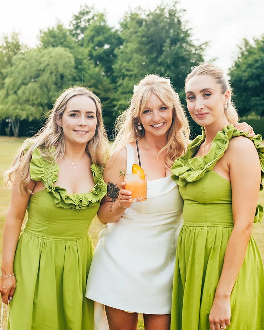 bride in short evening dress with standing in between her bridesmaids
