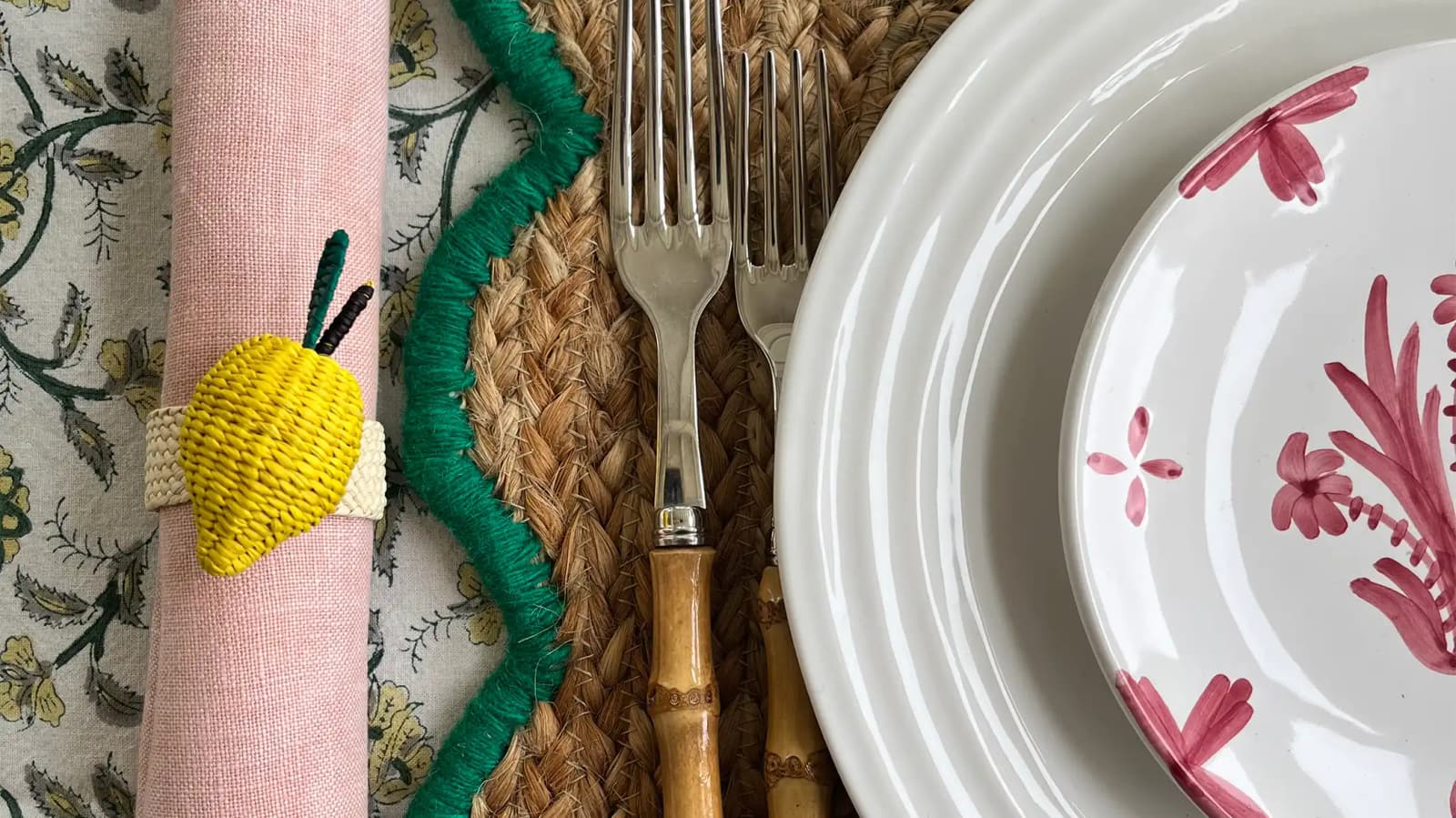 Colourful summer dinner tablescape featuring wedding presents including lemon napkin holder, handpainted plate and cutlery with bamboo handle on a patterned tablecloth.