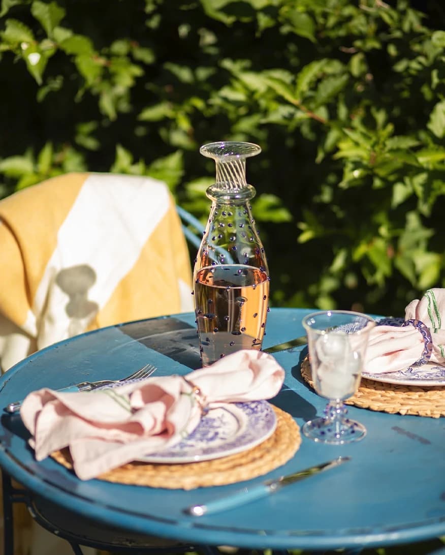 Issy Granger Pom Carafe is placed on a sun-lit alfresco table in the garden
