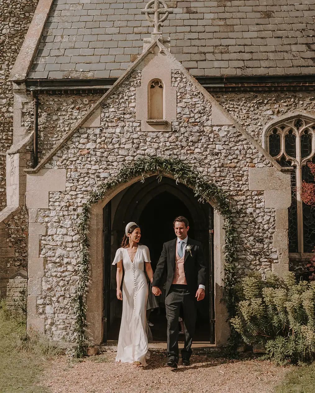 Groom and bride leave their wedding venue, traditional English church, after their wedding ceremony