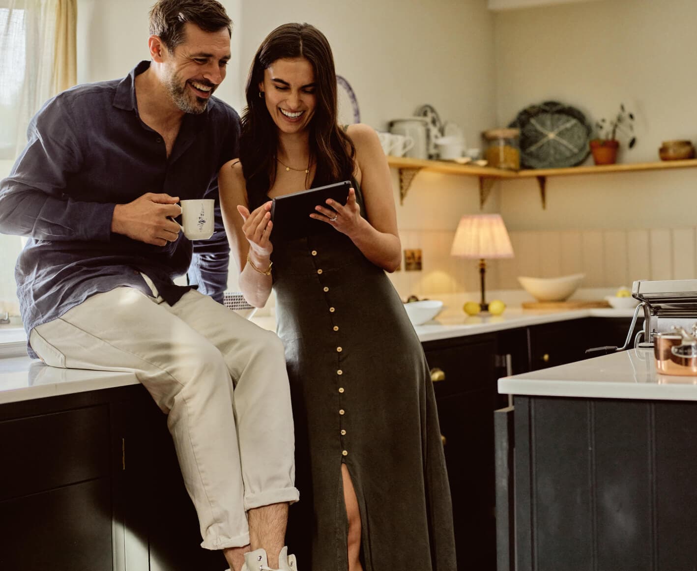 Couple in the kitchen looking at ipad with coffee in hand