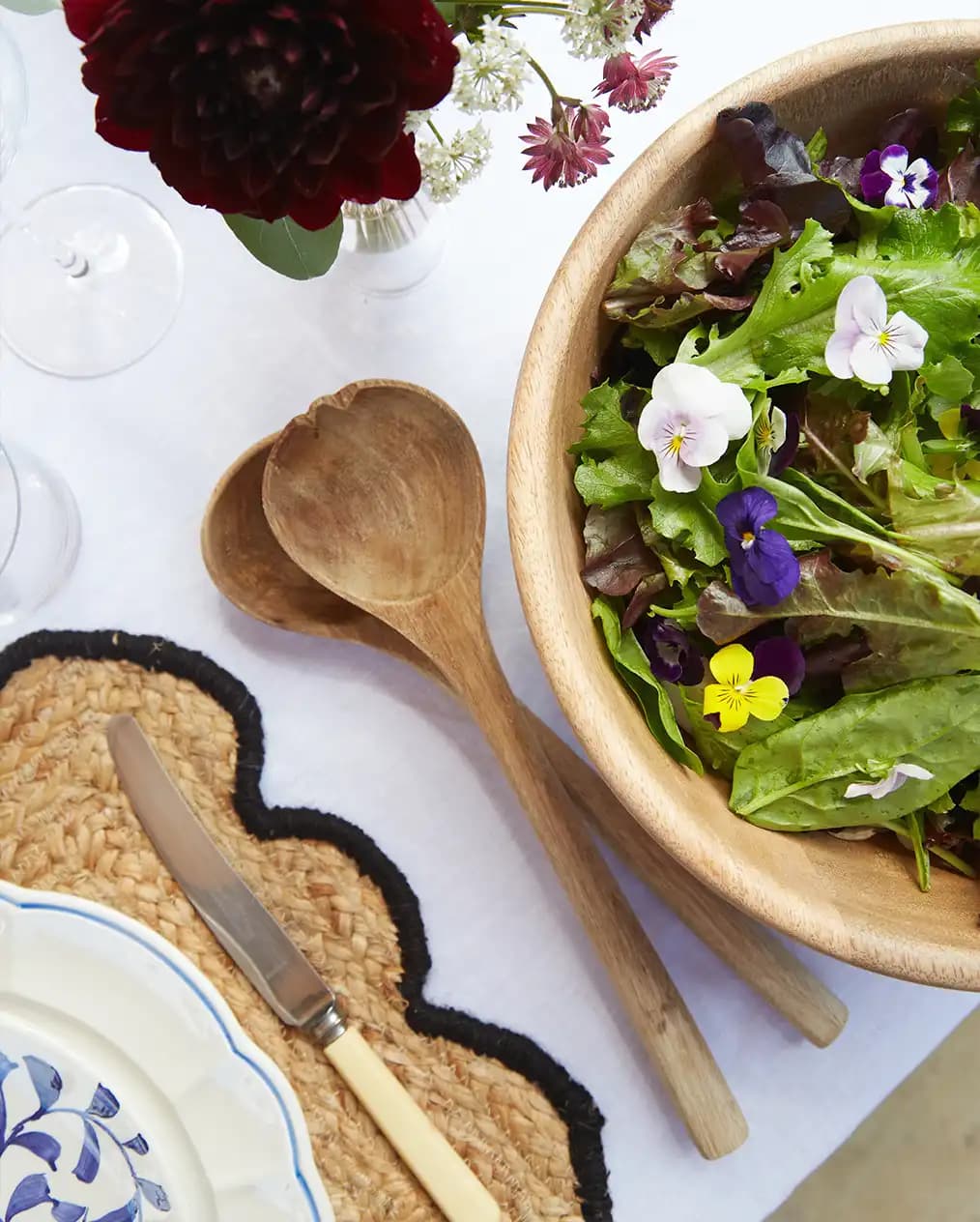 Tableware wedding presents of white tablecloth: wooden bowl, scalloped place mat and handpainted plate.