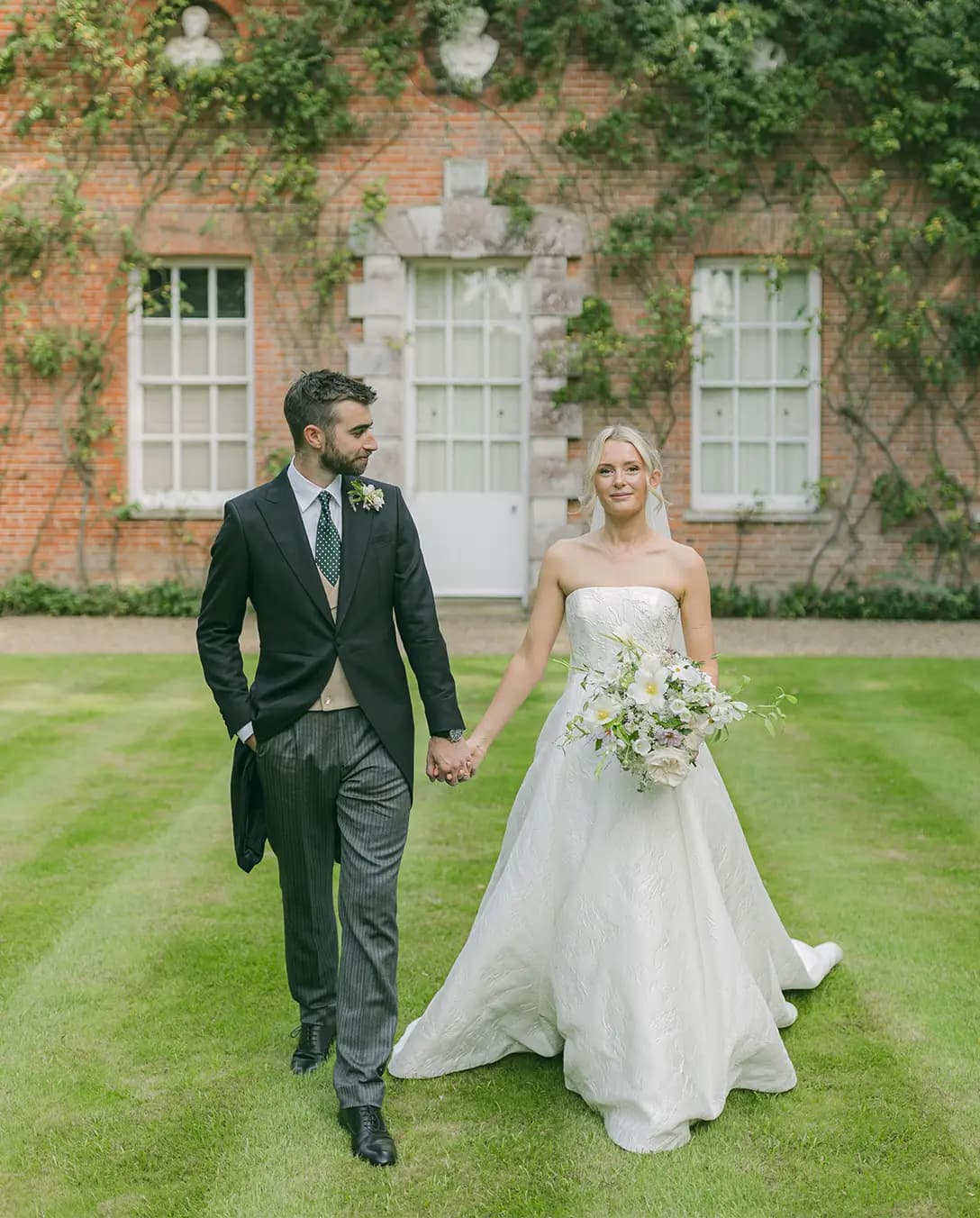 Bride and groom walk through their Hampshire country garden wedding venue