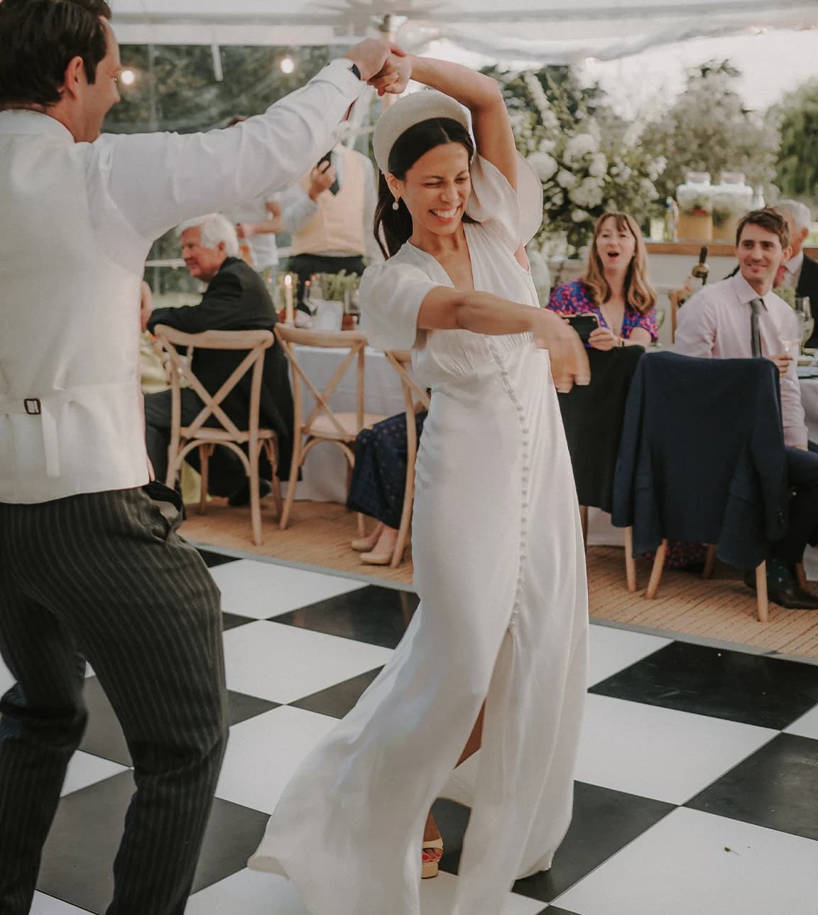 The bride and groom do their first dance on a dance floor in a marquee.