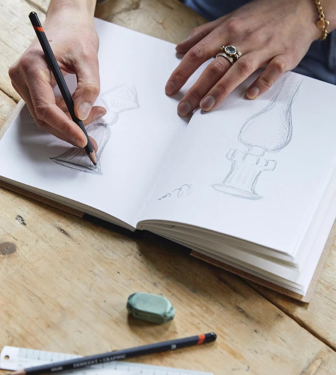 Issy Granger draws a design of her candlestick into a sketchbook
