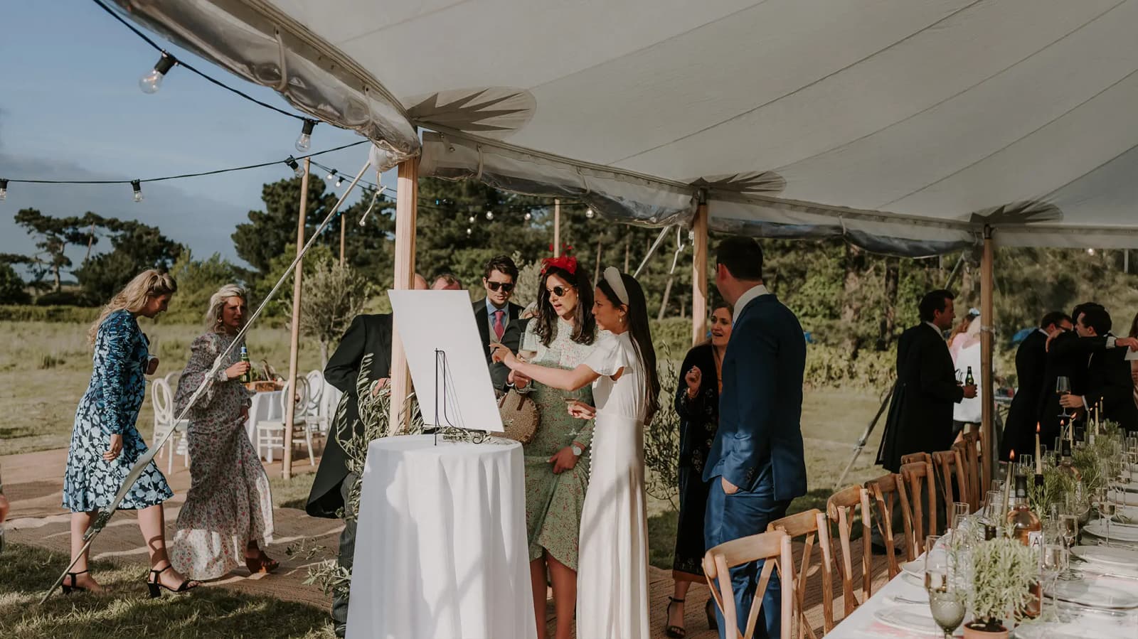 A bride shows wedding guests the marquee wedding seating plan