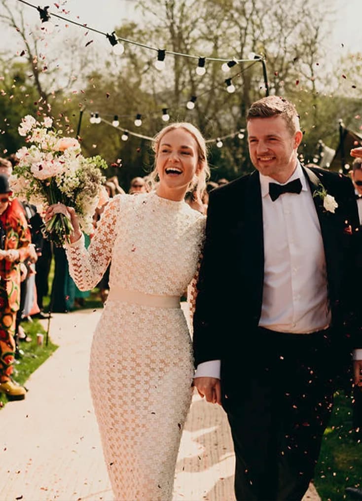 The Wedding Present Company bride and groom walk down the aisle while confetti are thrown at them.