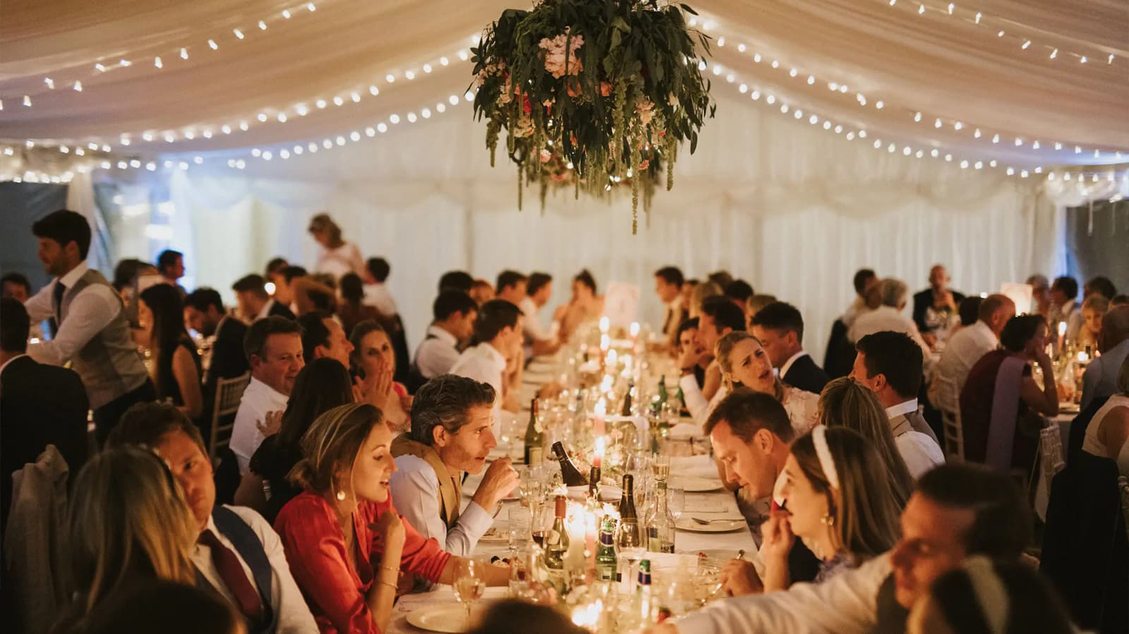 Wedding guests sitting in a marquee decorated with fairy lights