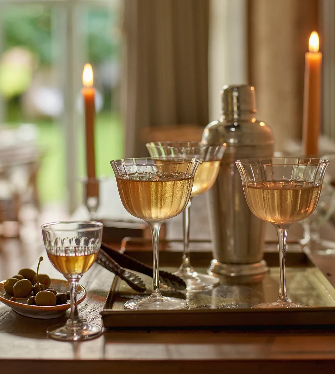 A tray with wedding presents for cocktails lovers features martini in cocktail coupe glasses next to a cocktail shaker.