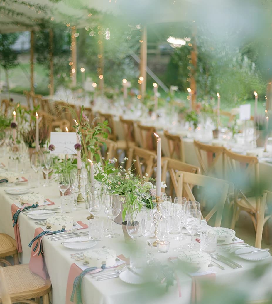 Pastel-toned wedding table adorned with garden flowers, gold candlesticks, and ivory tableware.