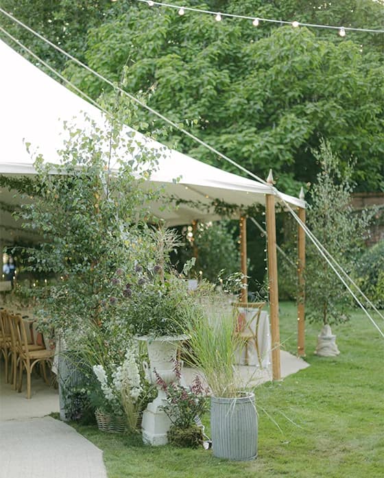 Entry to the traditional wedding marquee set in Hampshire's picturesque countryside, decorated with white and green foliage.