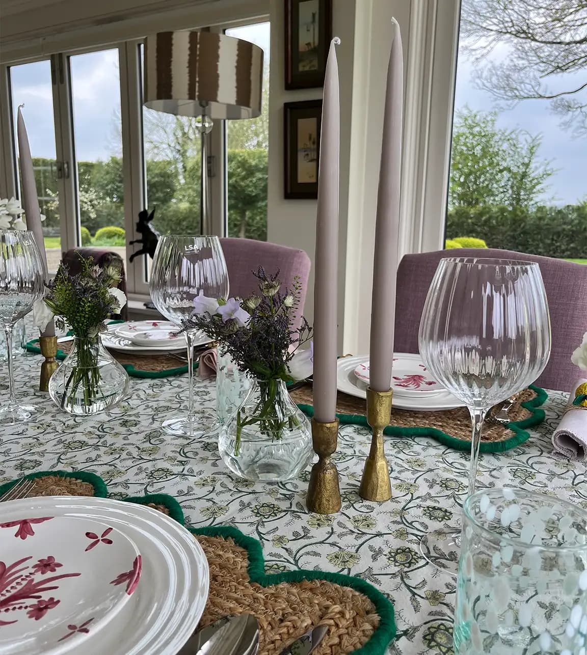 A dinner party tablescape by Georgia Hearn features wedding gifts from The Wedding Present Company including floral tablecloth, stylish glasseware, brass candles and hand-painted plates.