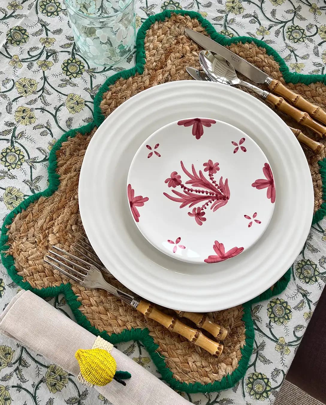 Colourful dinner tablescape styled by Georgia Hearn, featuring wedding presents including handpainted plates and cutlery on a patterned tablecloth.