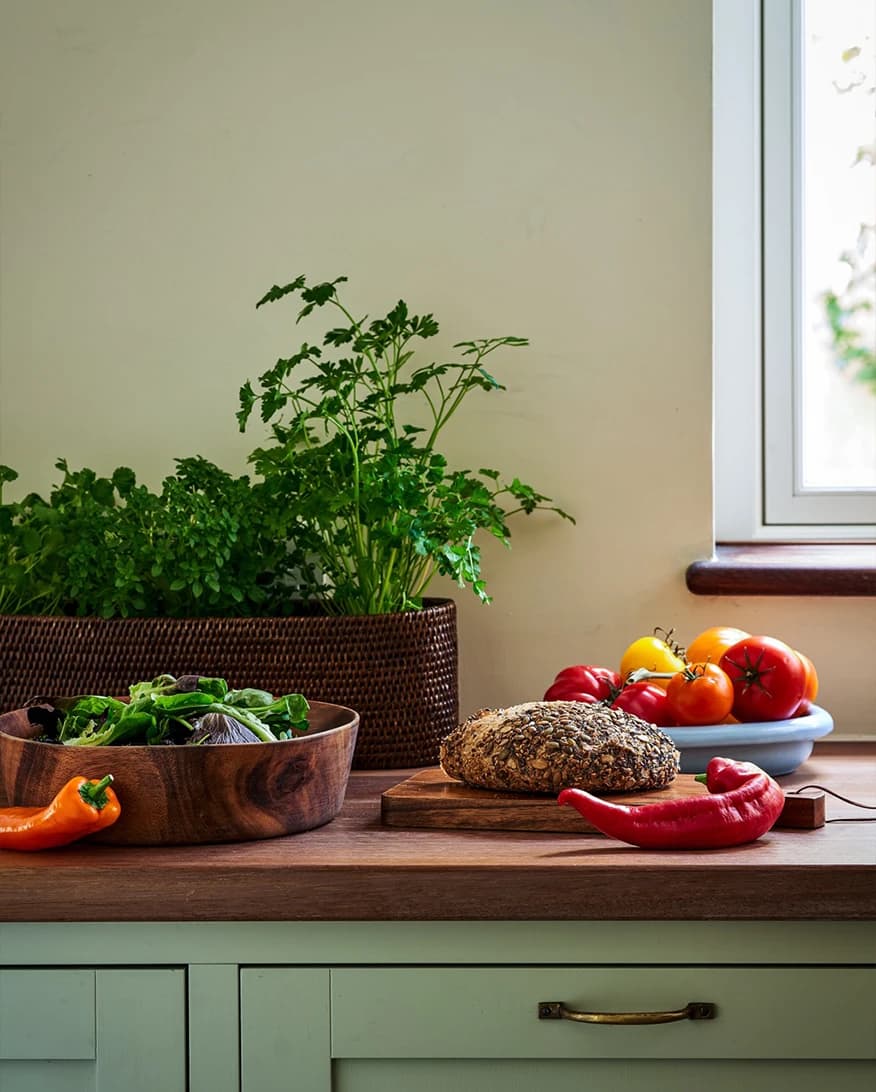 Kalinko rattan homeware gifts, bread basket and chopping boards, are displayed on traditional kitchen counter