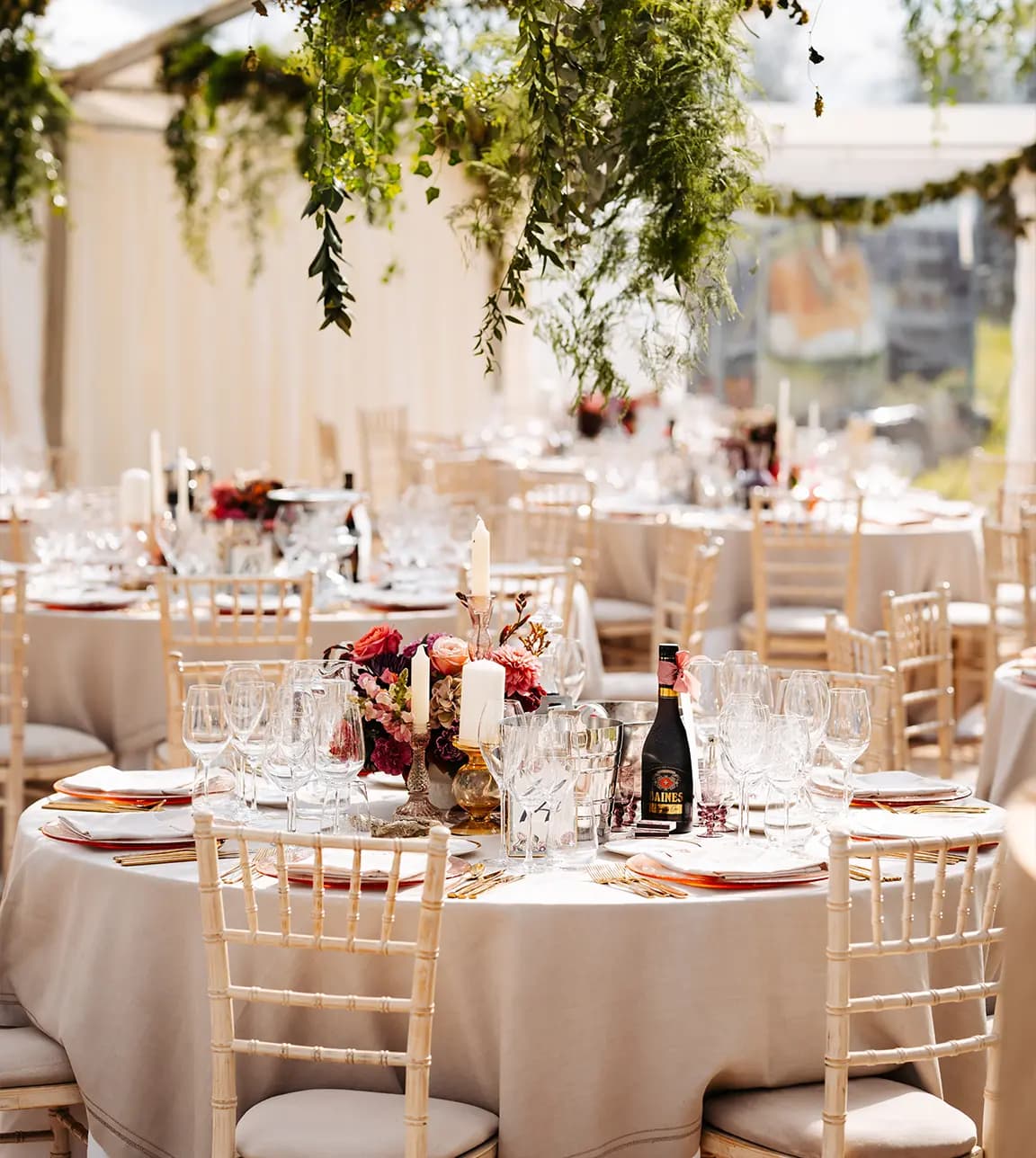 A wedding venue with hanging foliage and autumn wedding floral décor placed on cream tables 
