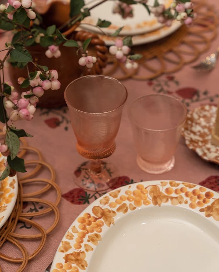 A close up of the cosy autumn-inspired tablescape featuring handpainted plates, rattan placemats and coloured-glasses.