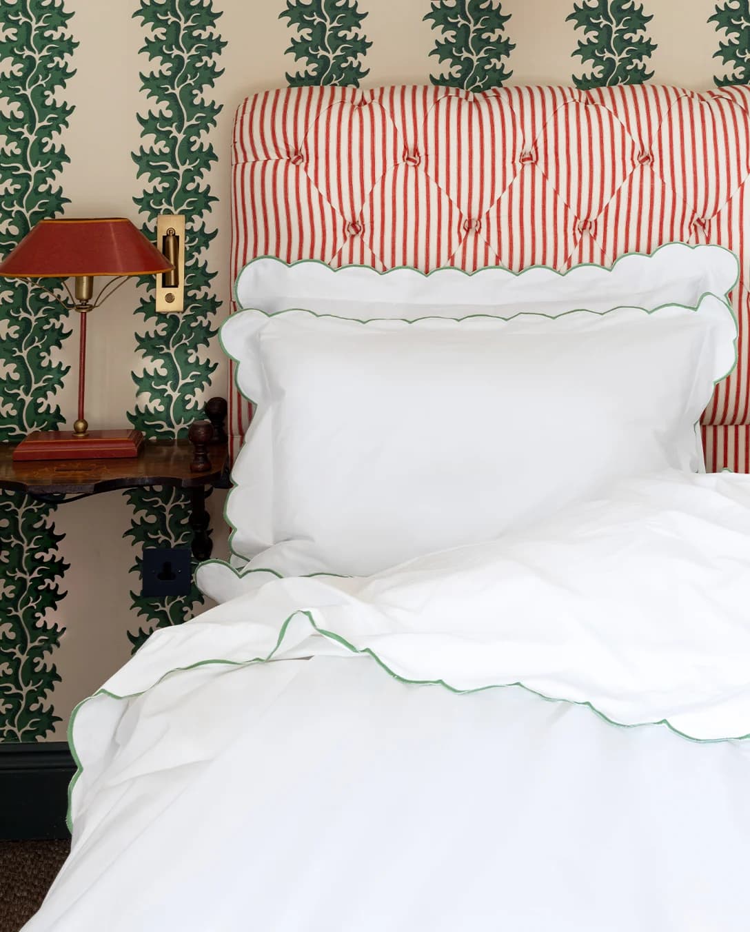 Stylish green bedroom with upholstered bed set with scalloped bed linen gifts from Rebecca Udall