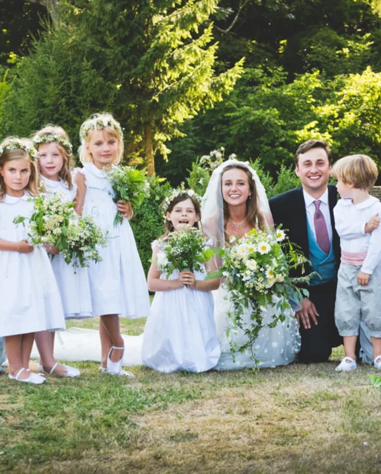 Traditional English bride and groom pose with flower boys and girls